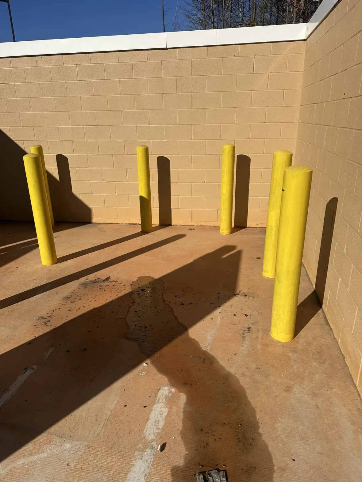 Commercial dumpster pad with grease stains before cleaning