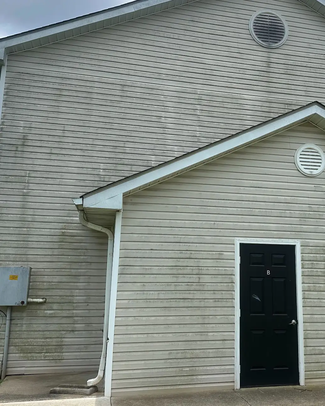 Commercial building siding with heavy staining before cleaning