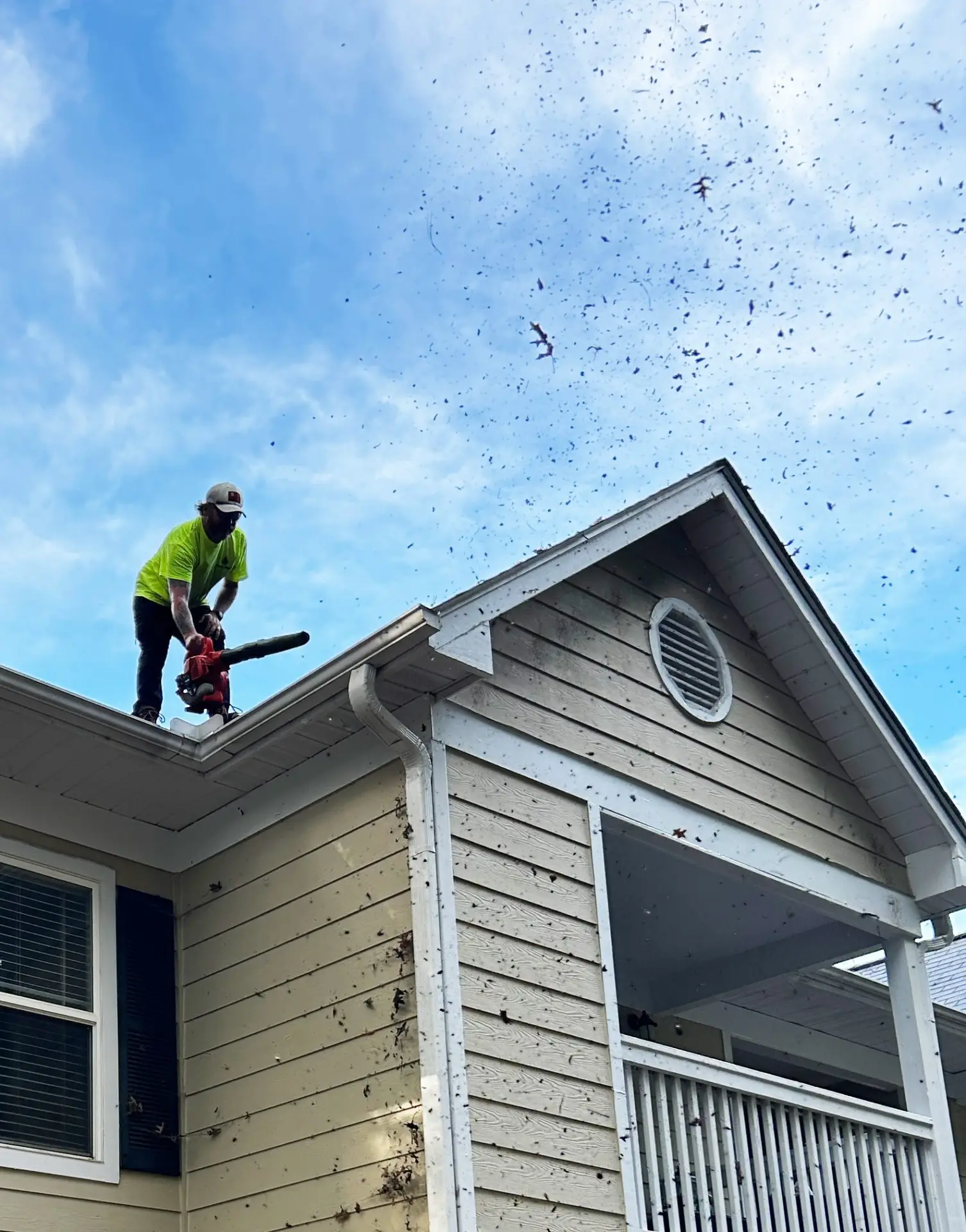 Worker removing debris from roof gutter system